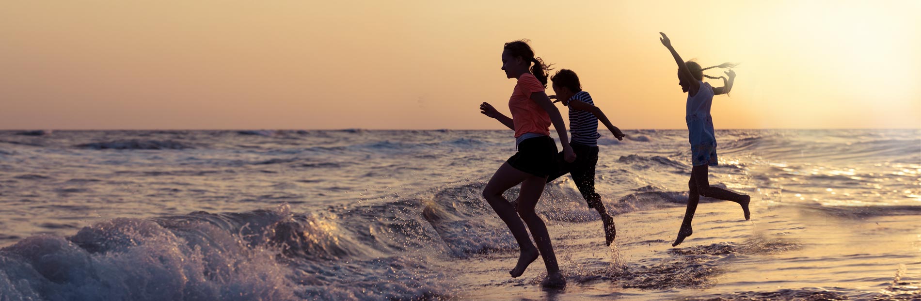 Children playfully jumping into ocean waves